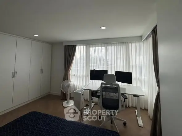 Modern study room with dual monitors and ergonomic chair, ample natural light through large windows.