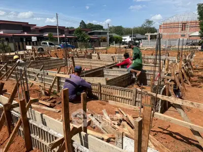 Construction site with workers building residential foundations under clear blue sky.