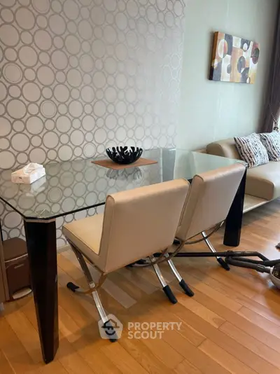 Modern dining area with glass table and stylish chairs in a contemporary living room setting.