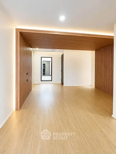 Spacious modern living room with wooden flooring and stylish ceiling lighting.