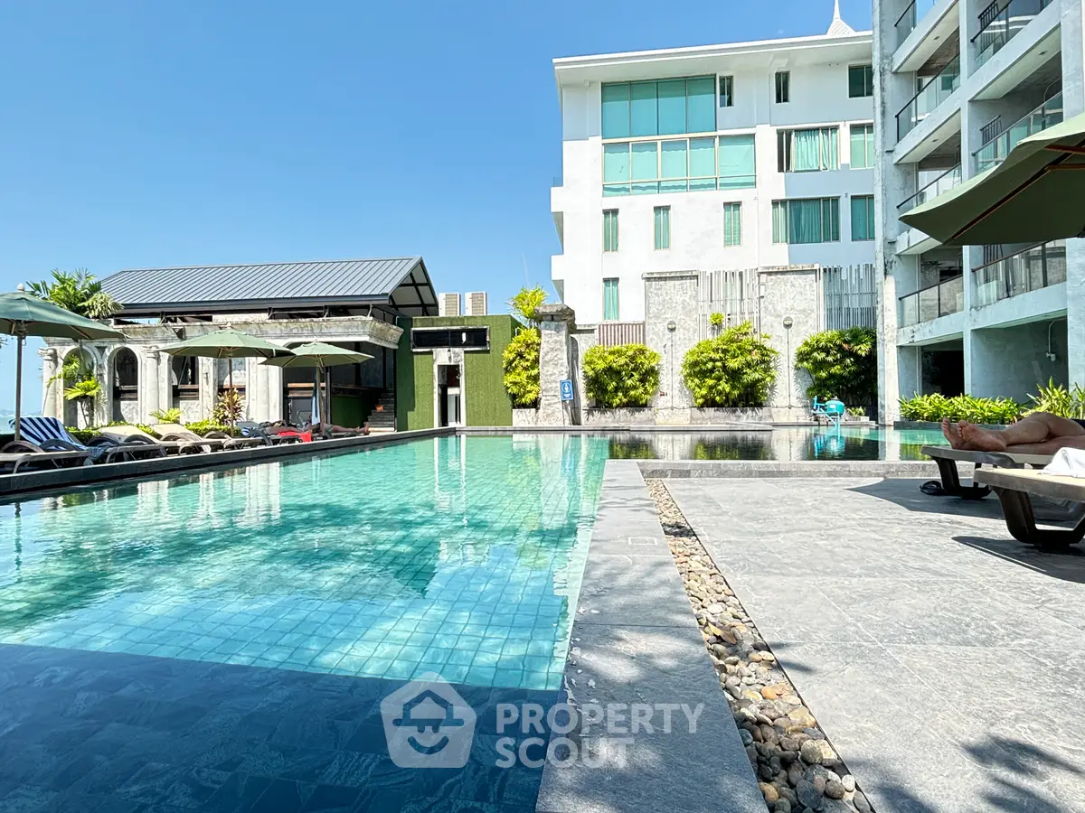 Luxurious apartment complex with stunning outdoor pool and modern architecture under clear blue sky.