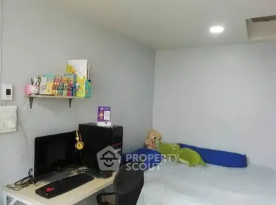 Cozy bedroom with study area featuring a computer setup and plush toys, ideal for a comfortable living space.