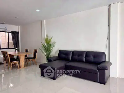 Spacious living room with modern leather sofa and dining area, perfect for family gatherings.