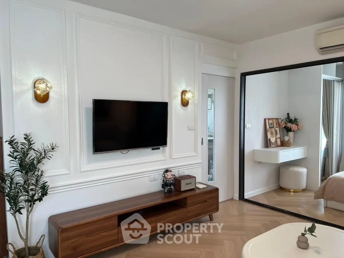 Modern living room with stylish decor and wall-mounted TV, featuring elegant lighting and wooden furniture.