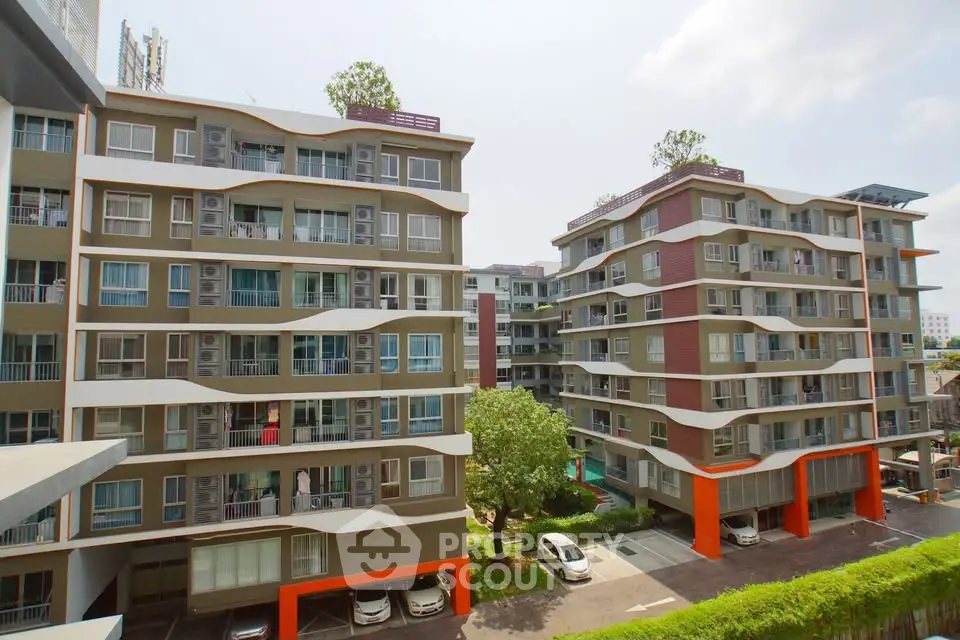 Modern apartment buildings with balconies and parking area in urban setting.