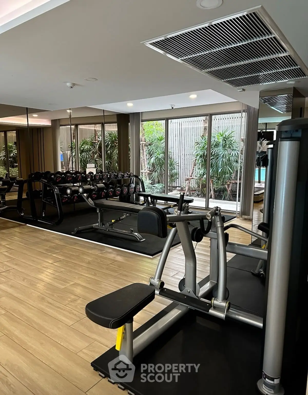 Modern gym with state-of-the-art equipment and large windows overlooking greenery.