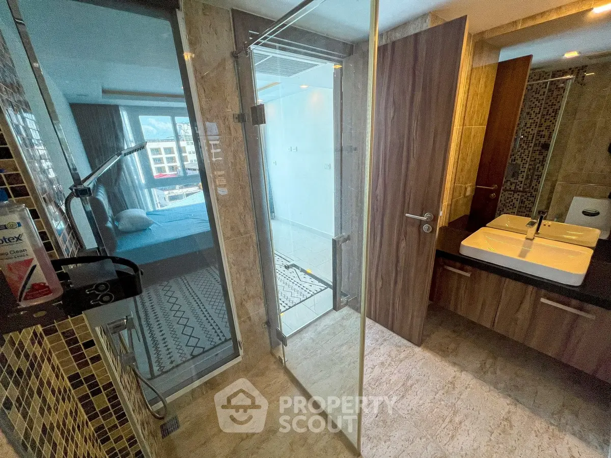 Modern bathroom with glass shower and view into bedroom