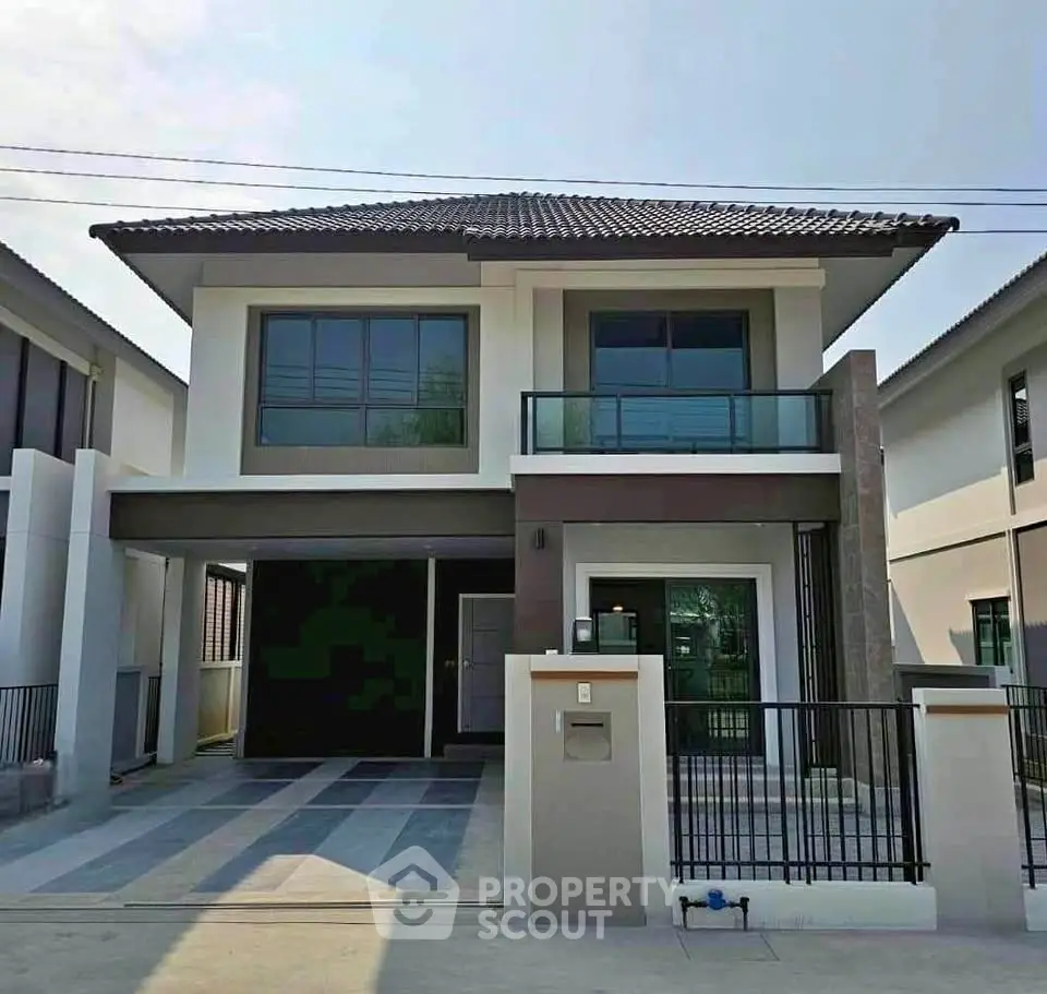 Modern two-story house with sleek design and spacious driveway in suburban neighborhood.