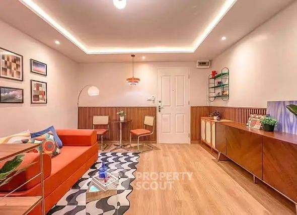 Stylish living room with modern decor, vibrant orange sofa, and elegant lighting in a cozy apartment.