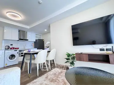 Modern open-plan living room with kitchen, featuring sleek furniture and wall-mounted TV.