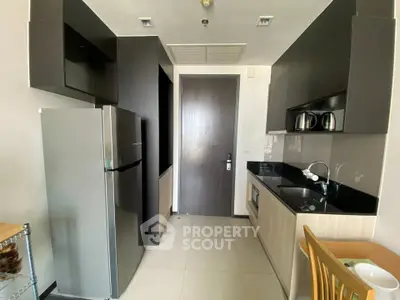 Modern kitchen with sleek black cabinetry and stainless steel appliances in a compact layout.