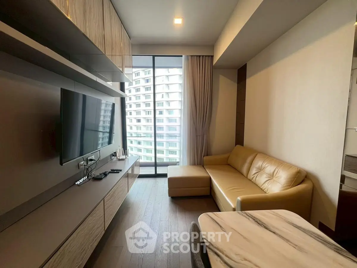 Modern living room with sleek design, featuring a large TV, comfortable sofa, and floor-to-ceiling windows.
