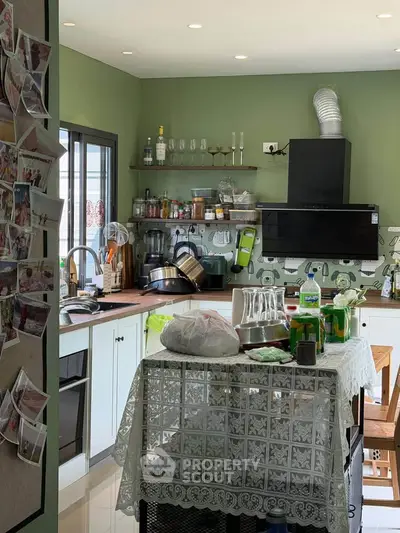 Charming kitchen with green walls and modern appliances, featuring an open layout and cozy dining area.