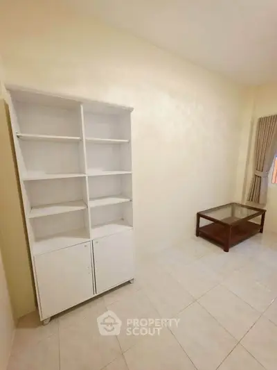 Spacious living room with white shelving and glass coffee table