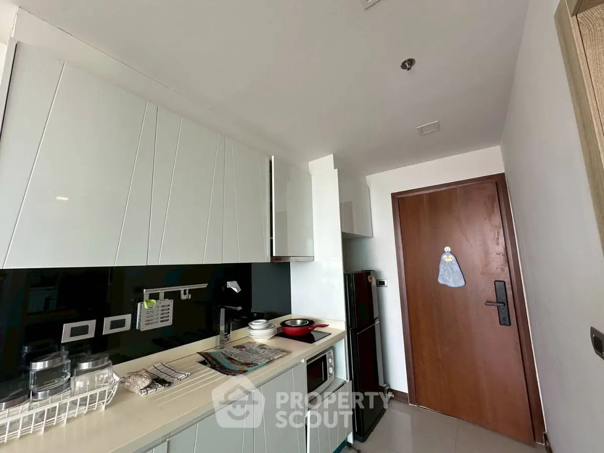 Modern kitchen with sleek cabinets and compact appliances in a cozy apartment.