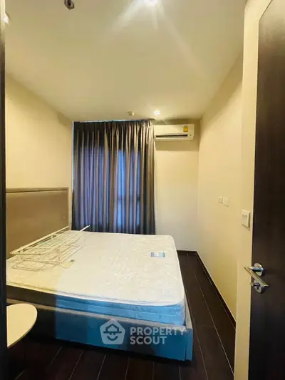 Cozy bedroom with a large window and air conditioning, perfect for restful nights.