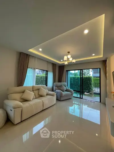 Spacious living room with modern lighting and garden view, perfect for relaxation and entertainment.