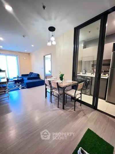 Modern open-plan living room with dining area and kitchen, featuring stylish decor and ample natural light.