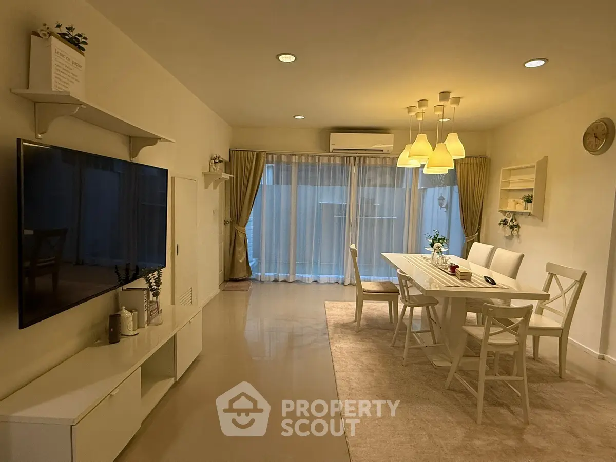 Elegant living room with modern dining area and large TV, featuring stylish lighting and floor-to-ceiling windows.