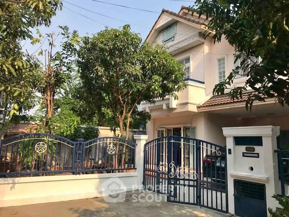 Charming two-story house with gated entrance and lush greenery