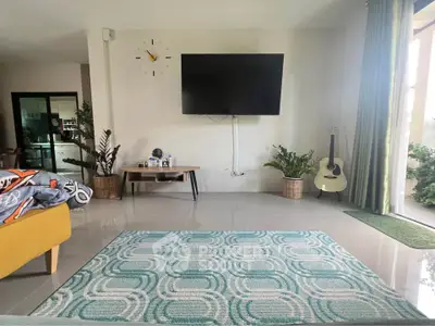 Spacious living room with modern decor, featuring a wall-mounted TV, stylish rug, and indoor plants.