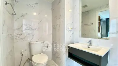 Modern bathroom with sleek fixtures and marble tiles, featuring a stylish sink and toilet.