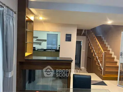 Modern open-plan living area with stylish kitchen and wooden staircase, perfect for family gatherings.
