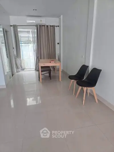 Spacious minimalist living area with sleek tile flooring and modern furniture.