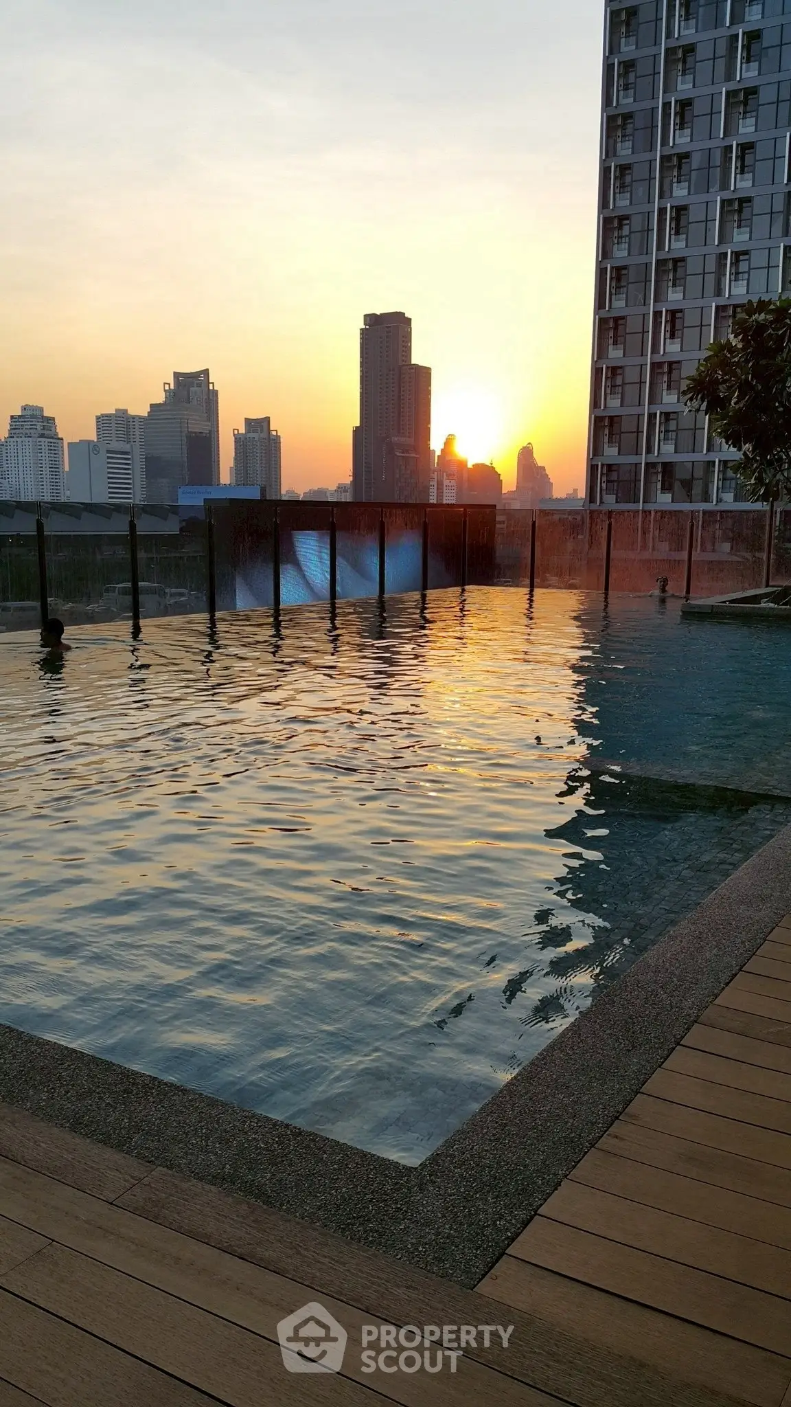 Stunning rooftop pool with city skyline view at sunset, perfect for luxury living.