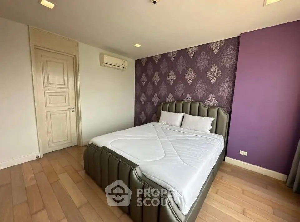 Modern bedroom with stylish purple accent wall and elegant bed in a cozy apartment.