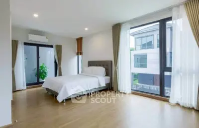 Spacious modern bedroom with large windows and elegant decor in a contemporary home.
