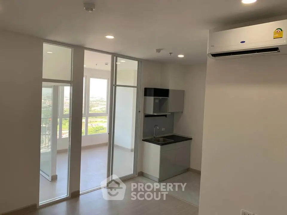 Modern apartment with open kitchen and balcony view, featuring sleek design and ample natural light.