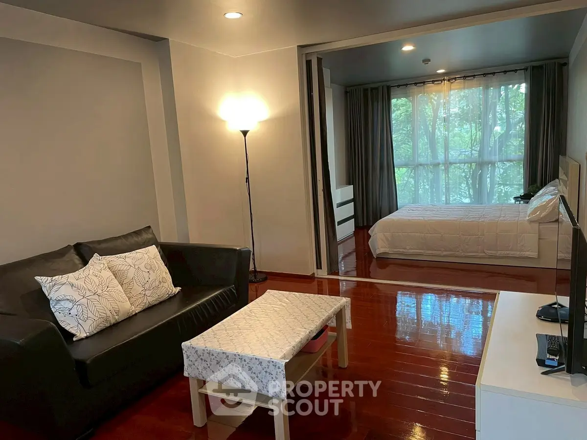 Cozy studio apartment with open living and bedroom area, featuring modern furnishings and large window views.