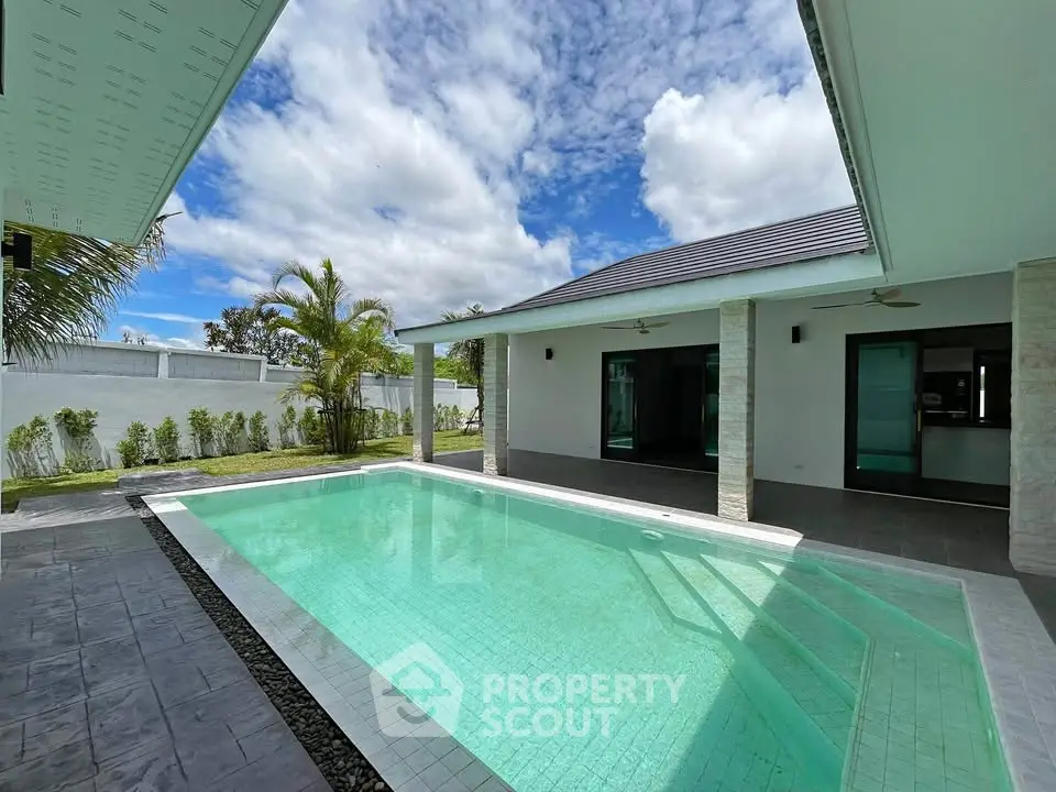 Luxurious modern villa with private pool and spacious outdoor area under a clear blue sky.