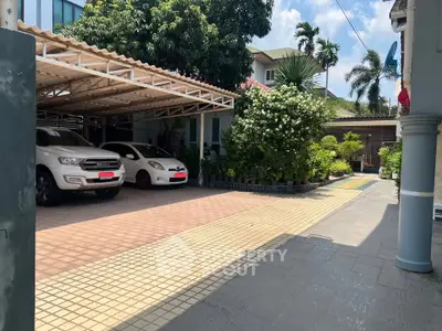 Spacious residential parking area with covered carport and lush greenery.