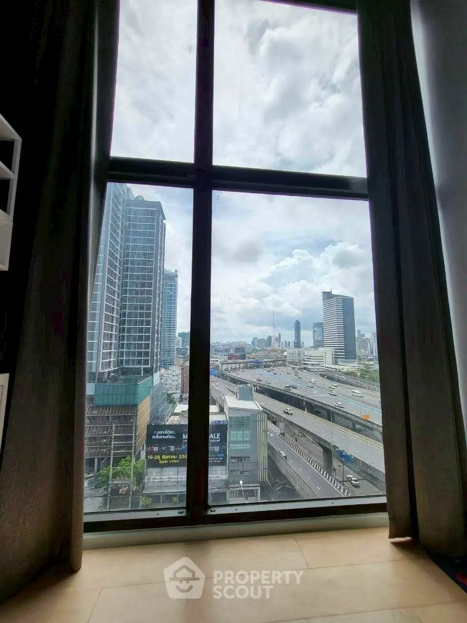 Stunning urban view from high-rise apartment window overlooking city skyline and highway.