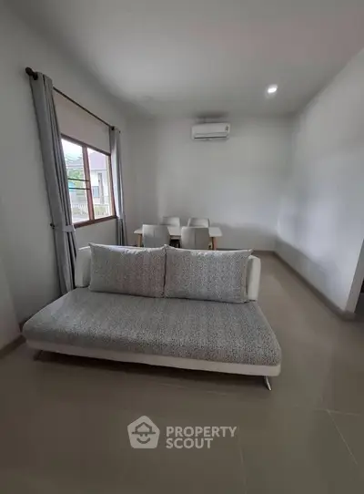 Modern living room with sleek sofa and dining area, featuring minimalist design and natural light.