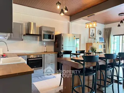 Spacious modern kitchen with island, sleek appliances, and stylish lighting in a cozy home setting.
