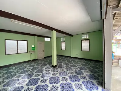 Spacious room with patterned tile flooring and green walls, ideal for versatile use.