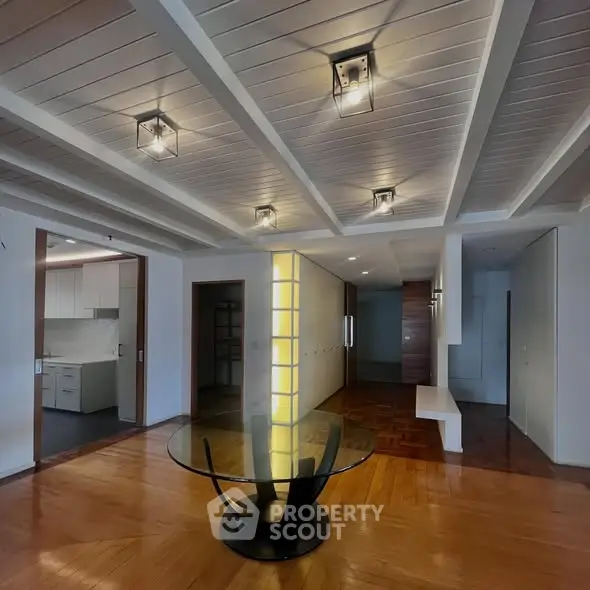 Spacious modern living area with stylish lighting and open kitchen view.