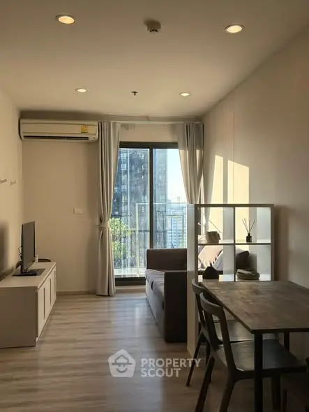Modern living room with balcony view in high-rise apartment, featuring sleek furniture and natural light.