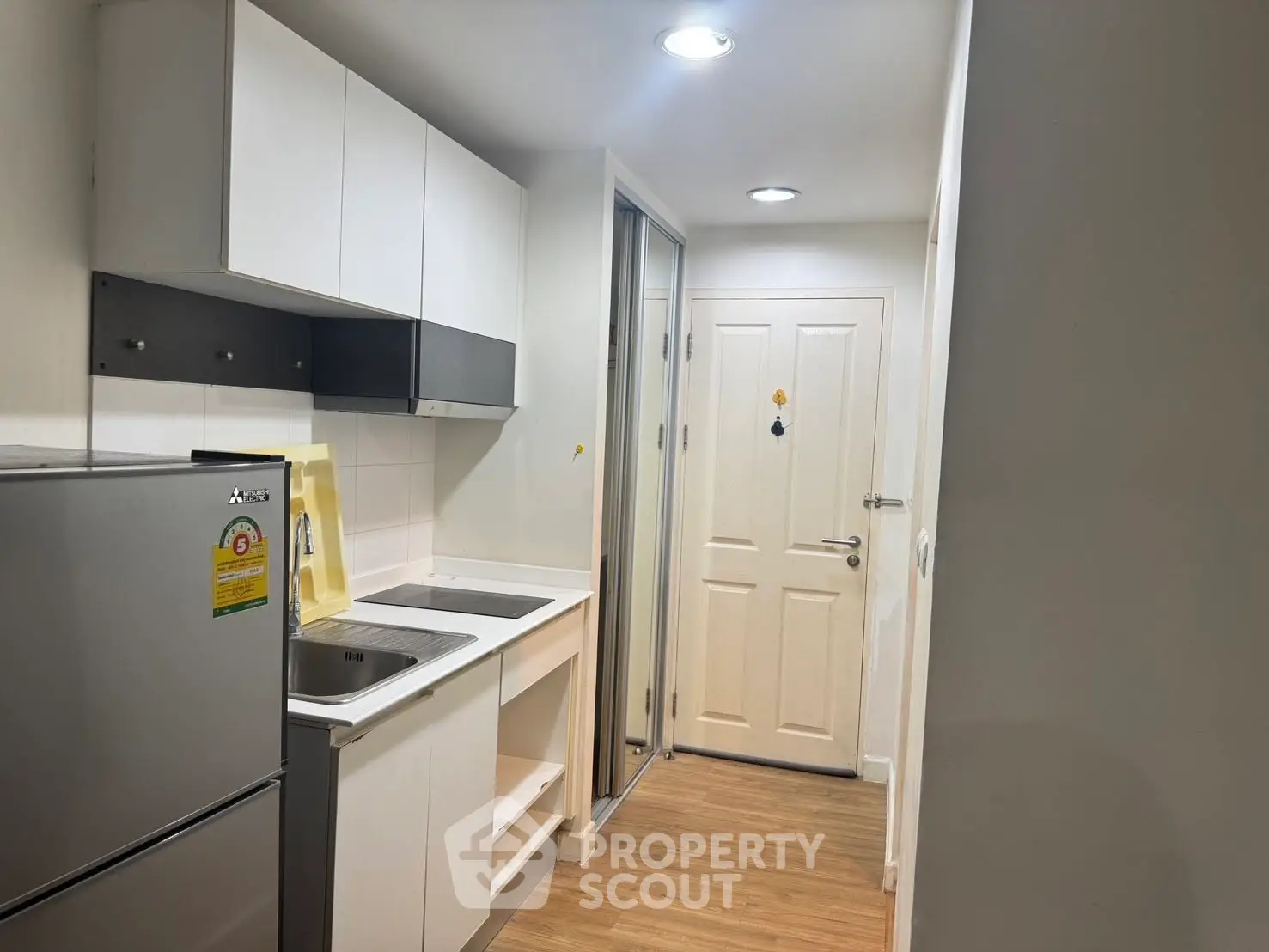 Compact modern kitchen with sleek cabinetry and stainless steel appliances in a cozy apartment.