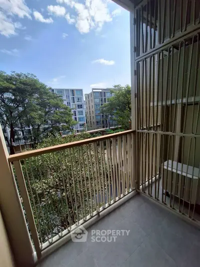 Charming balcony with serene view of modern apartment complex and lush greenery.