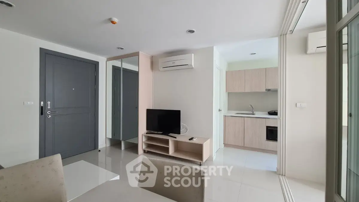 Modern apartment interior with open kitchen and living area, featuring sleek design and air conditioning.