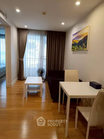 Cozy living room with modern decor and natural light, featuring a small dining table and comfortable seating.