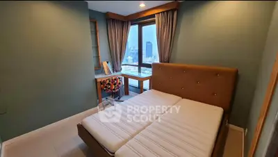 Cozy bedroom with city view, featuring a stylish bed and a study desk by the window.