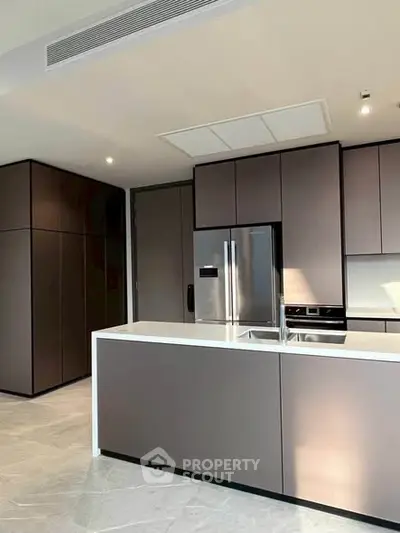 Modern kitchen with sleek cabinetry and stainless steel appliances in luxury apartment.