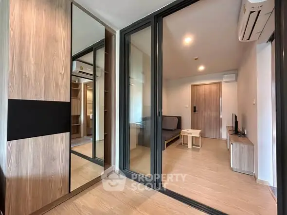 Modern living room with wooden flooring and glass sliding doors in a stylish apartment.