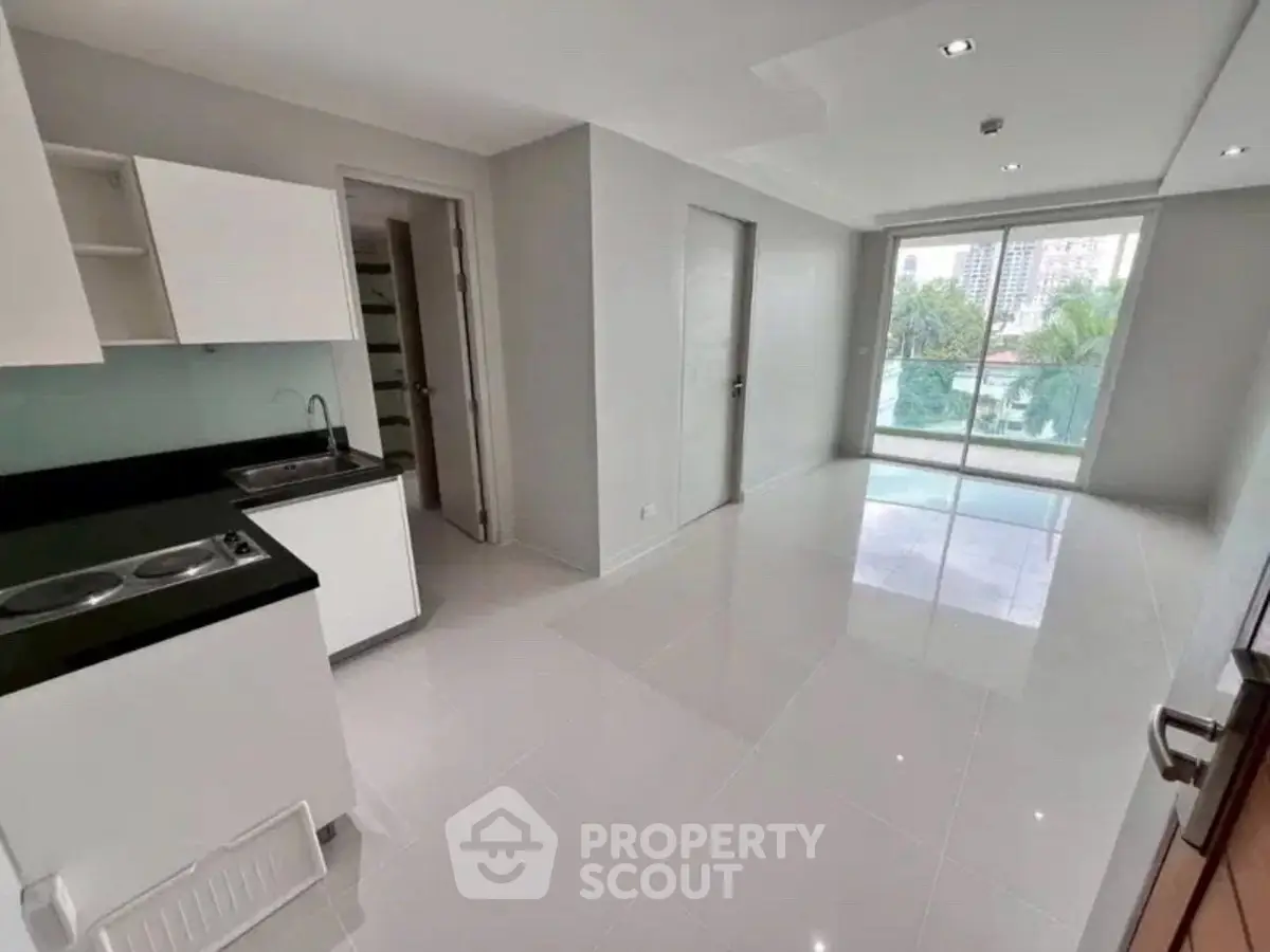 Modern open-layout kitchen with sleek design and balcony view in a bright apartment.