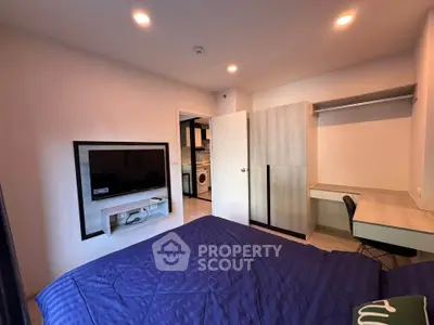 Modern bedroom with built-in wardrobe and wall-mounted TV in stylish apartment.